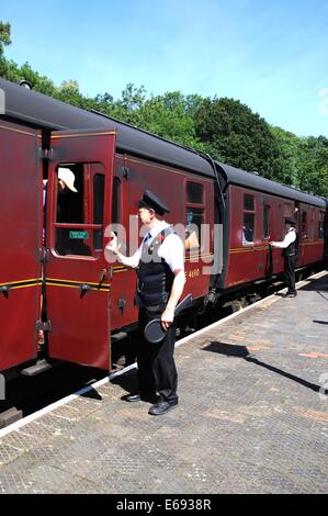 Porters alongside the LMS/British Rail Maroon railway carriages ready to help passengers disembark, Highley, Worcestershire, UK. Stock Photo