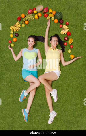 Young women lying on grass with fruits Stock Photo