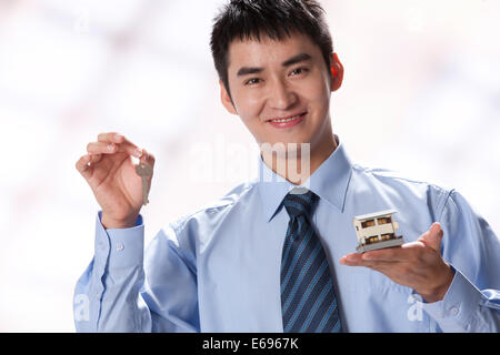Young businessman holding key and artificial house Stock Photo