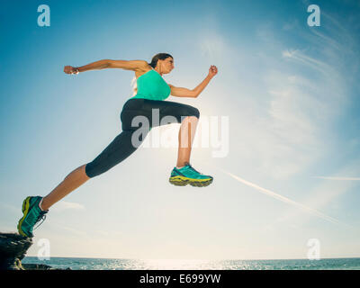 Caucasian woman running on beach Stock Photo