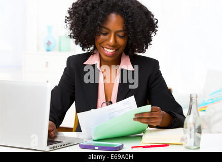 Mixed race businesswoman reading papers at desk Stock Photo