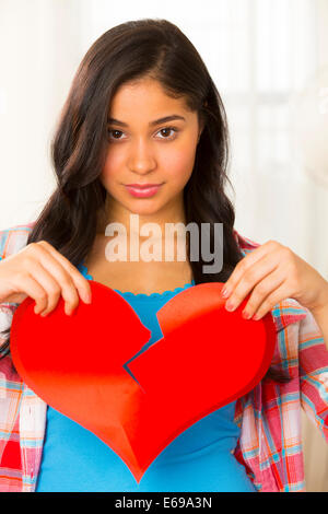 Hispanic woman holding broken heart Stock Photo