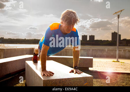 Caucasian man doing push ups in urban park Stock Photo