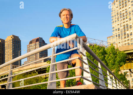 Caucasian man leaning on railing in urban park