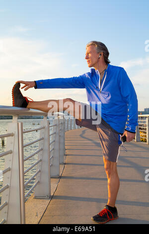 Caucasian runner stretching on urban waterfront Stock Photo