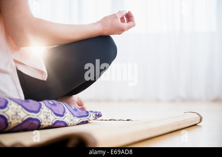 Caucasian woman meditating on yoga mat Stock Photo