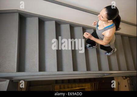 Caucasian woman running up stairs Stock Photo