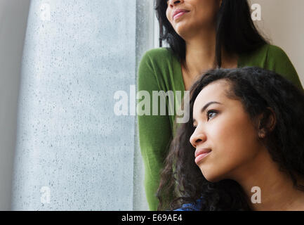 Mother and daughter daydreaming at window