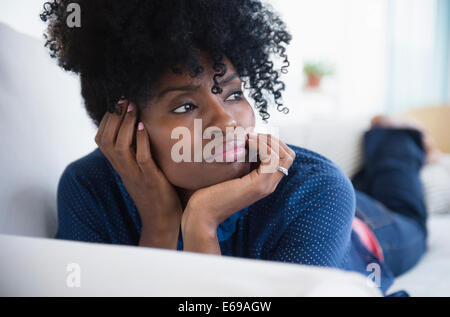 Black woman laying on sofa Stock Photo