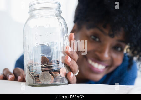 Black woman saving coins in jar Stock Photo