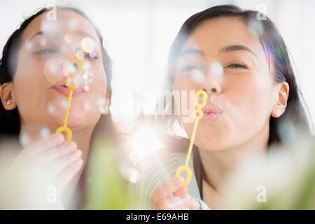 Women blowing bubbles together Stock Photo