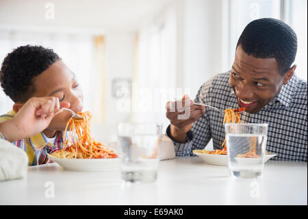 Father and son eating together at table Stock Photo
