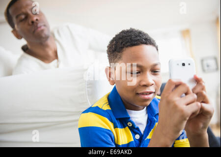 Father watching son use cell phone Stock Photo