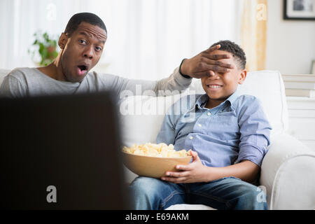 Father and son watching television on sofa