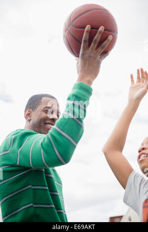 Father and son playing basketball outdoors Stock Photo