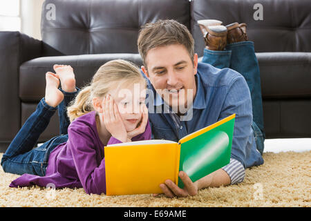 Caucasian father and daughter reading in living room Stock Photo