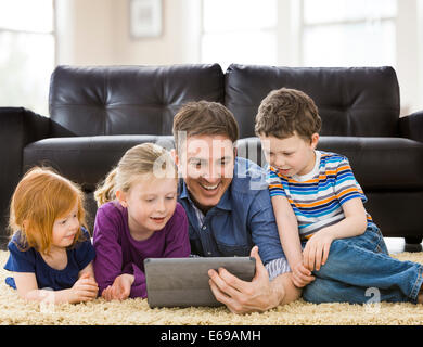 Caucasian father and children using tablet computer in living room Stock Photo