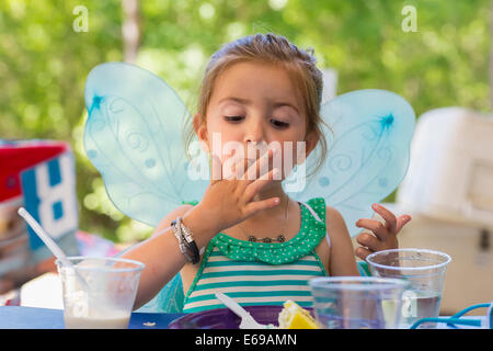 Caucasian girl eating cake at birthday party Stock Photo