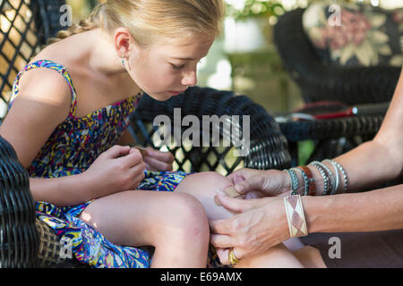 Caucasian mother putting bandage on daughter's knee Stock Photo