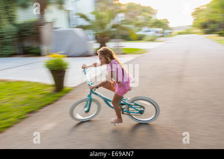 Caucasian girl riding bicycle on street Stock Photo