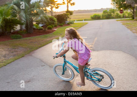 Caucasian girl riding bicycle on street Stock Photo