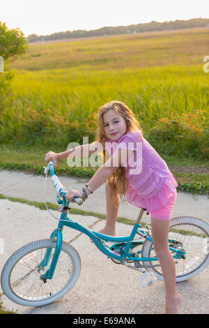 Caucasian girl riding bicycle on rural street Stock Photo