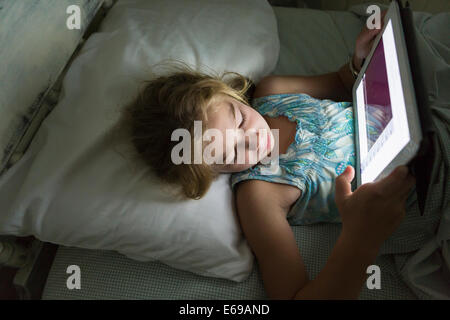 Caucasian girl using tablet computer in bed Stock Photo