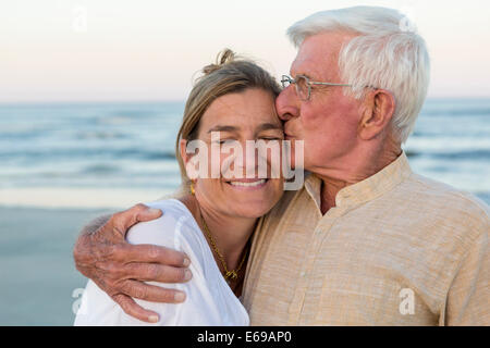 Caucasian father kissing daughter on beach Stock Photo