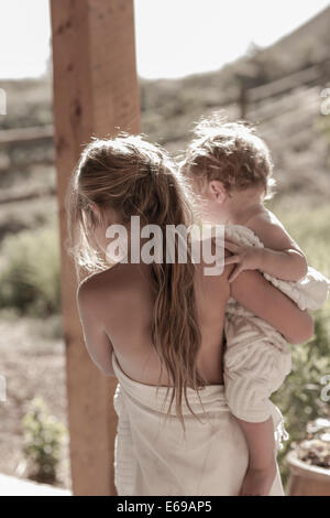 Caucasian girl carrying baby brother on porch Stock Photo