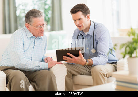 Caucasian doctor and patient using digital tablet at home Stock Photo