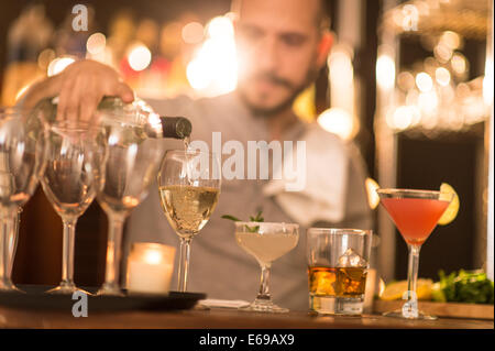 Hispanic bartender pouring drinks at bar Stock Photo