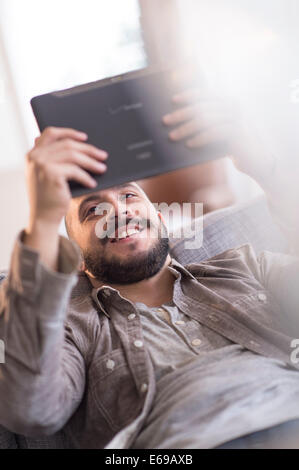 Hispanic man using digital tablet on sofa Stock Photo