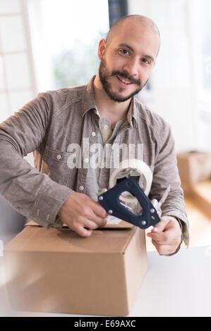 Hispanic man taping cardboard box Stock Photo