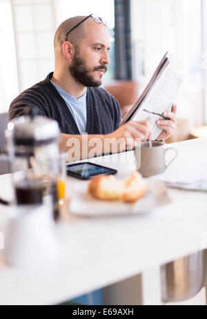 Hispanic man reading newspaper at breakfast Stock Photo