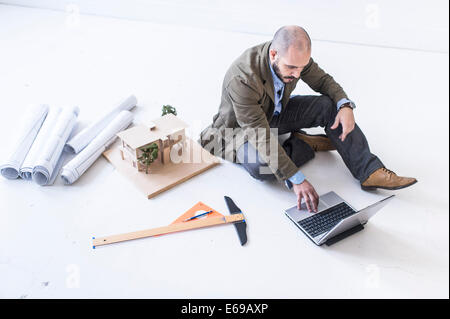 Hispanic architect using laptop on floor Stock Photo