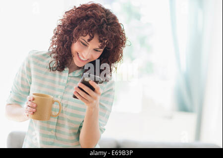 Hispanic woman using cell phone in living room Stock Photo