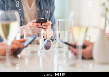 People using cell phones at dinner table Stock Photo