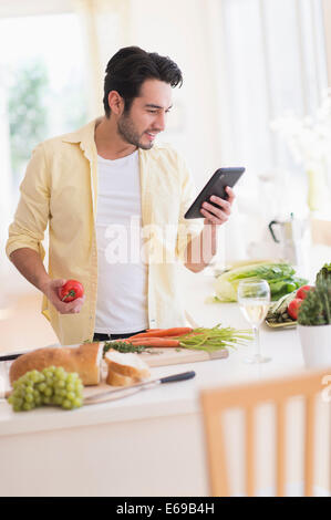 Mixed race man cooking with digital tablet in kitchen Stock Photo