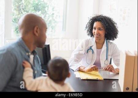 Father with baby talking to doctor Stock Photo