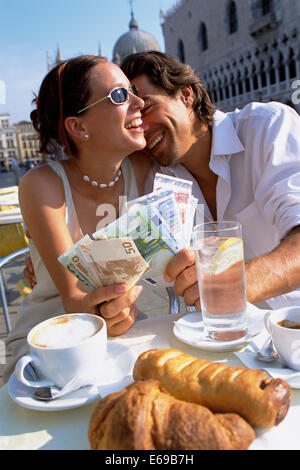 Couple with wads of cash having breakfast at cafe Stock Photo