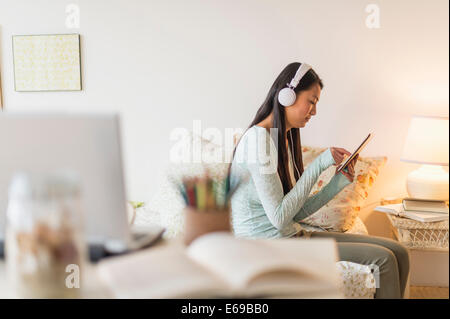 Mixed race teenage girl using digital tablet on bed Stock Photo