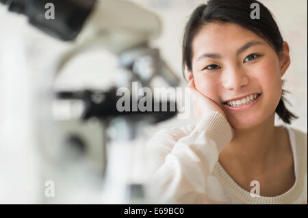 Mixed race teenage girl smiling in science lab Stock Photo