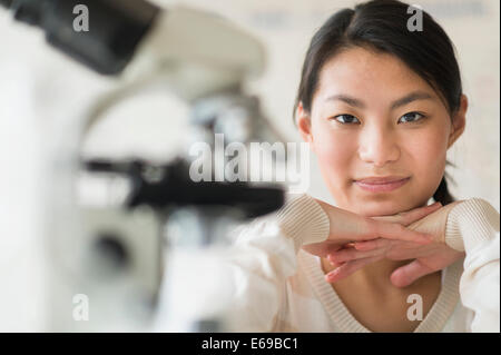 Mixed race teenage girl smiling in science lab Stock Photo