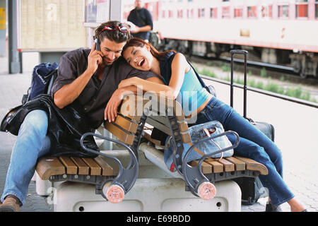 Couple relaxing at train station Stock Photo