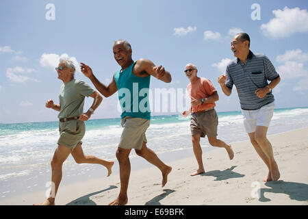 Senior couples jogging on beach Stock Photo