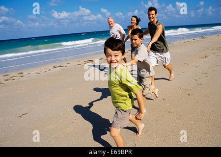 Caucasian family running on beach Stock Photo