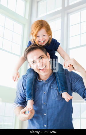 Caucasian father carrying daughter on shoulders