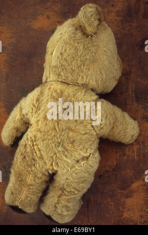 Vintage worn beige teddy bear sitting on front lip of drawer in antique ...