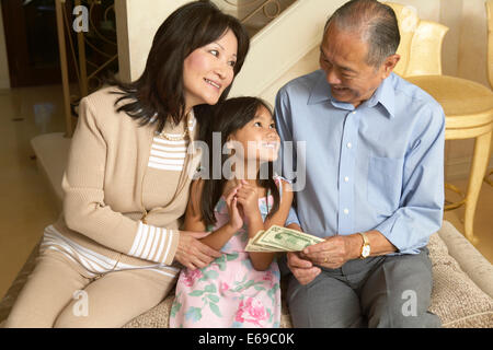 Senior couple giving granddaughter money Stock Photo