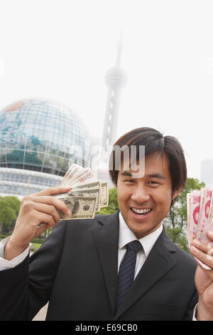 Chinese businessman holding wads of money, Shanghai, China Stock Photo